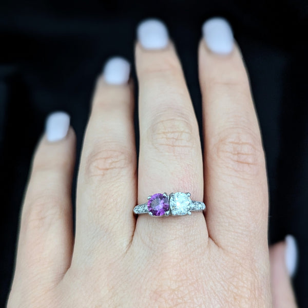 This exquisite vintage toi et moi ring beautifully captures the romanticism of the classic two-stone design, a symbol of two souls intertwined. The ring showcases an old European cut diamond paired with a lovely purplish- pink sapphire. Toi et moi jewelry, historically popularized in the 18th and 19th centuries, gained significant prominence when Napoleon Bonaparte gifted Josephine a similar ring, forever embedding this style in the narrative of love and partnership. Today, this design is a popular choice f