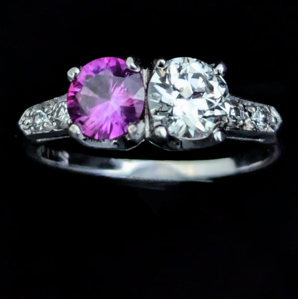 This exquisite vintage toi et moi ring beautifully captures the romanticism of the classic two-stone design, a symbol of two souls intertwined. The ring showcases an old European cut diamond paired with a lovely purplish- pink sapphire. Toi et moi jewelry, historically popularized in the 18th and 19th centuries, gained significant prominence when Napoleon Bonaparte gifted Josephine a similar ring, forever embedding this style in the narrative of love and partnership. Today, this design is a popular choice f
