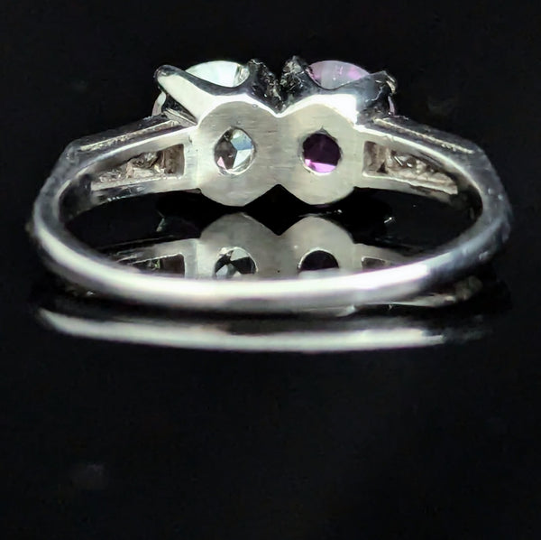 This exquisite vintage toi et moi ring beautifully captures the romanticism of the classic two-stone design, a symbol of two souls intertwined. The ring showcases an old European cut diamond paired with a lovely purplish- pink sapphire. Toi et moi jewelry, historically popularized in the 18th and 19th centuries, gained significant prominence when Napoleon Bonaparte gifted Josephine a similar ring, forever embedding this style in the narrative of love and partnership. Today, this design is a popular choice f