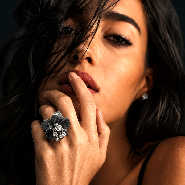Close-up of a woman's hand with a decorative ring on a dark background