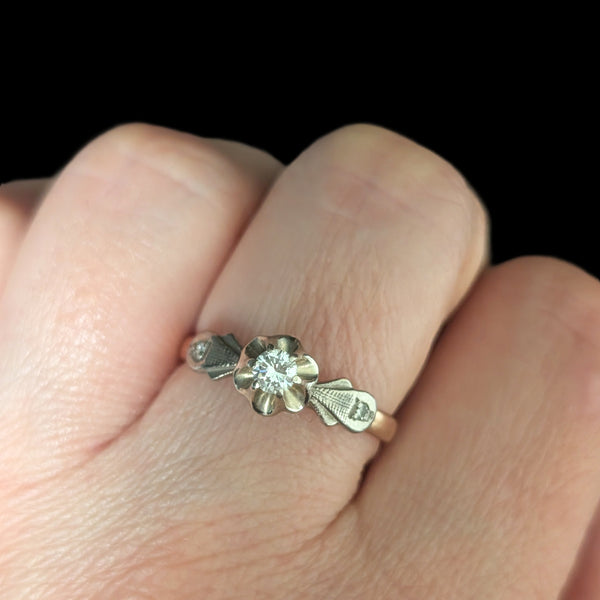 Gold ring with a diamond on a finger against a black background