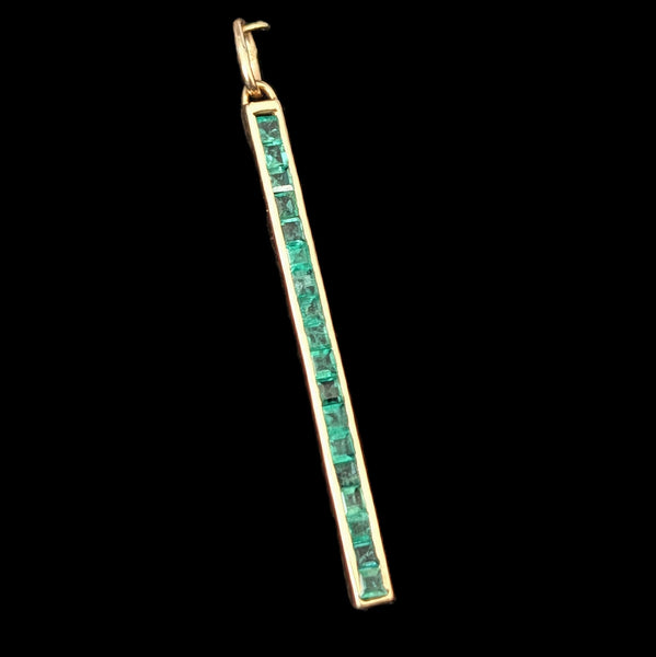 Gold pendant with emerald stones on a black background