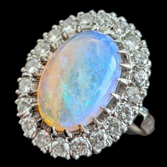 Ring with a large opal stone and diamond accents on a black background